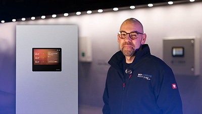 MTF Shop Samsung Klimaanlage Wärmepumpe Österreich | Ein MTF-Samsung Servicetechniker steht vor einer Samsung EHS Wärmepumpe mit integriertem Touch-Display. Das Bild führt zu einem Video, das die Vorteile von Samsung Heizsysteme zeigt.
